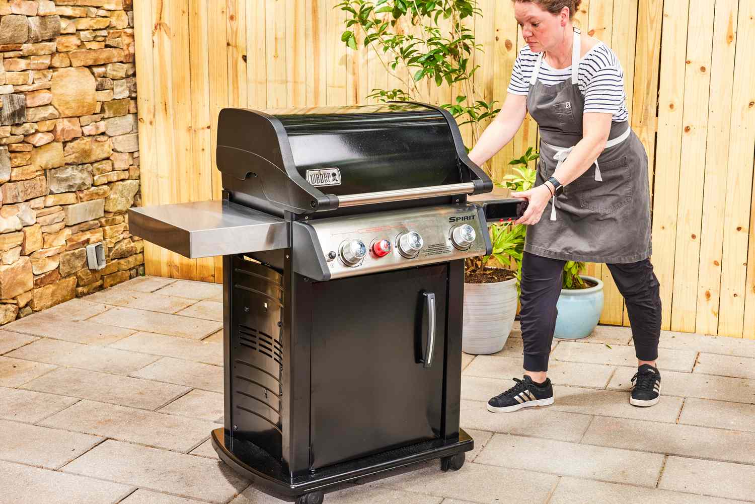 A person wheels the Weber Spirit EX-325s Smart Grill across a patio
