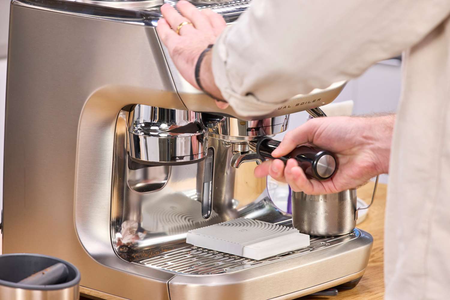 A person adjusts the portafilter on the Breville The Oracle Dual Boiler Espresso Machine
