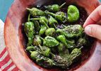 A small wooden bowl of grilled Padrón peppers sprinkled with salt. 
