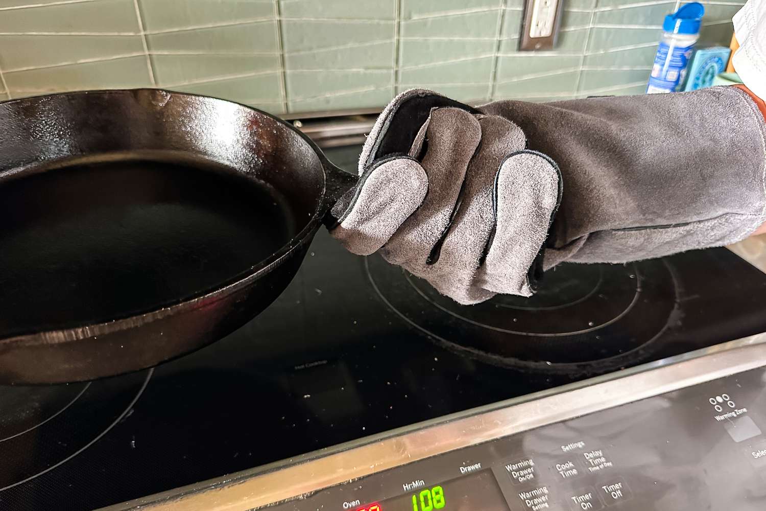 A person holds a pan while wearing the Breeo Fire Pit Gloves