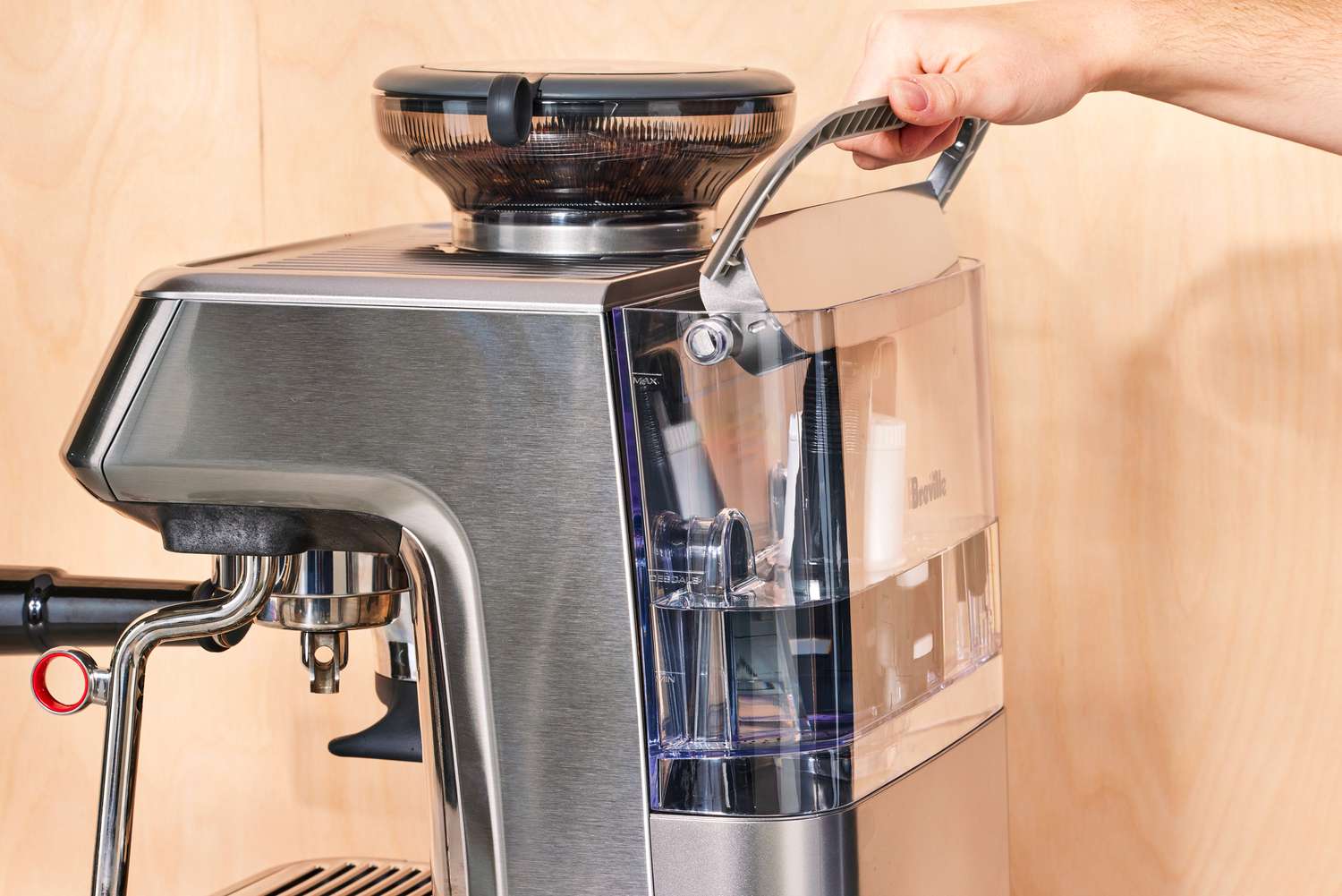 A person lifting up the handle of the water container of the Breville Barista Touch Impress Espresso Machine with Grinder