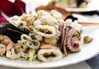 Italian seafood salad with calamari, scallops, shrimp, and mussels on a white plate.