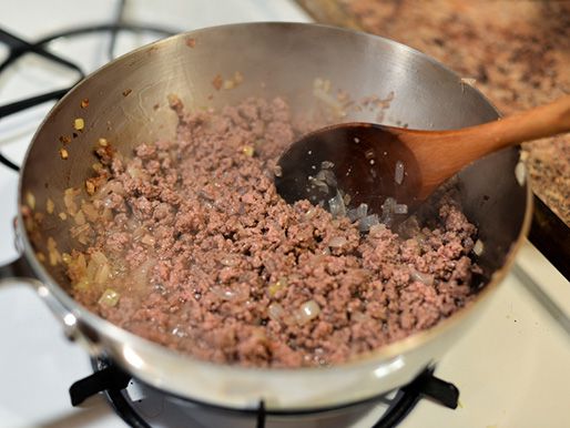 Ground beef cooking with onions in a pan.