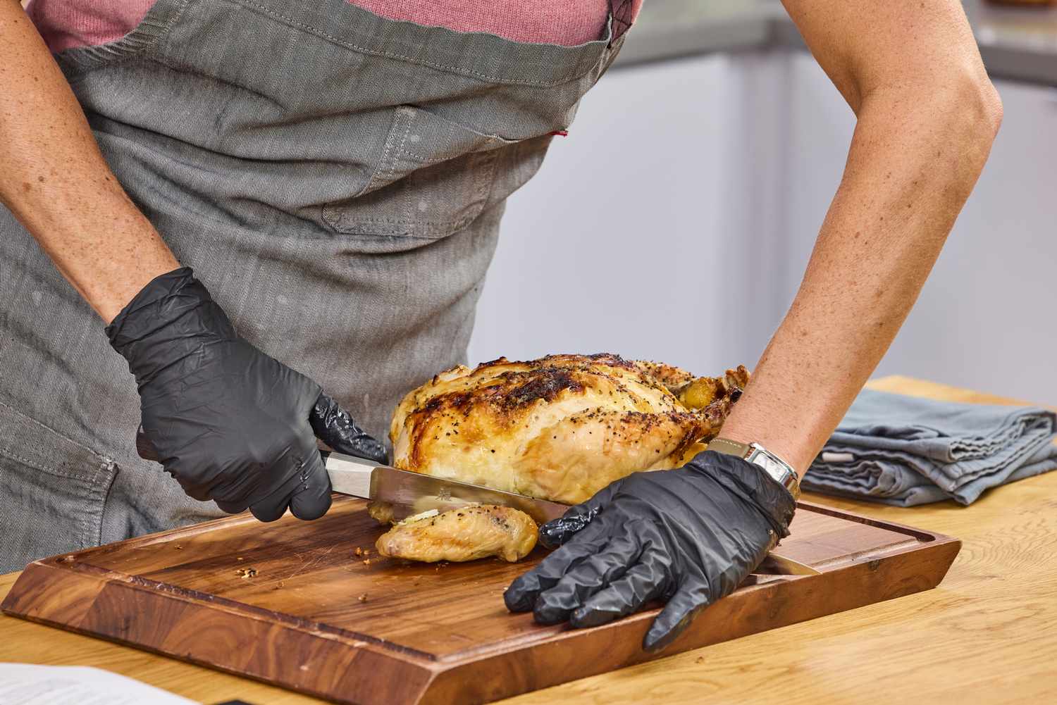 A person cuts a chicken with the Miyabi Koh 9.5 Inch Slicing Knife