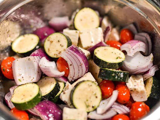 Tossing vegetables and cheese in the vinaigrette.
