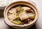 A clay pot filled with Frozen Simmered Tofu Soup with Pork, Cabbage, and Rice Noodles with rice alongside
