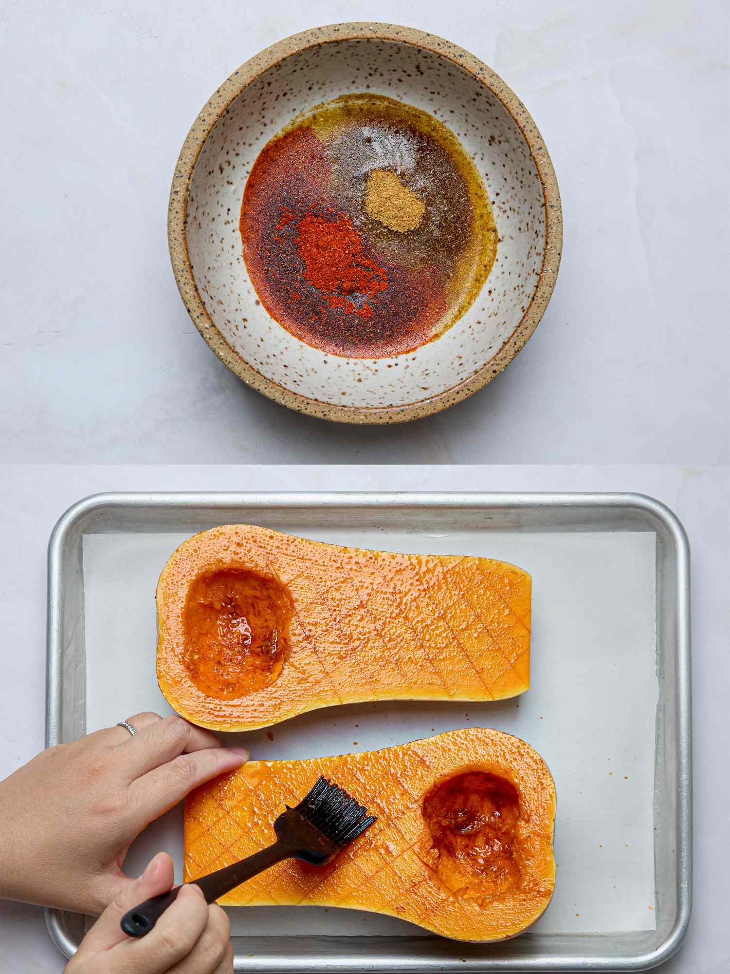 Bowl of spices and oil near brushed butternut squash halves with visible scored surfaces on a tray