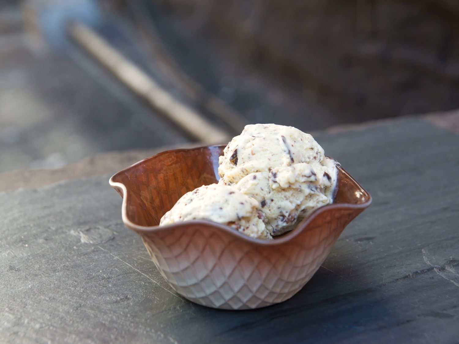 A glass ice cream dish with a waffle cone pattern filled with almond joy ice cream.