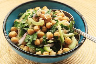 A blue bowl filled with a salad of chickpeas, celery, Italian parsley, and sliced shallots. 