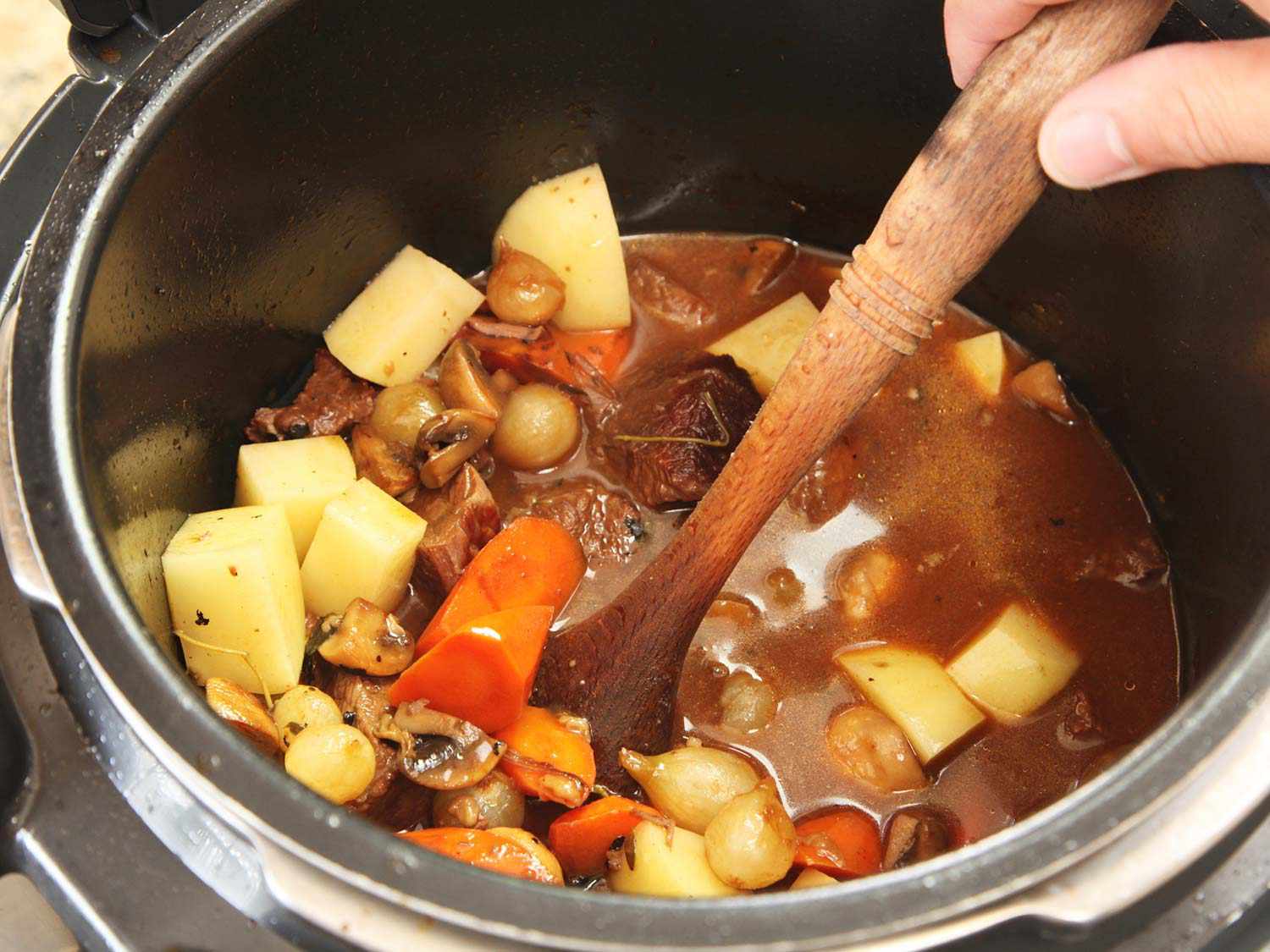 Tossing the ingredients for beef stew in a pressure cooker. 