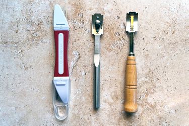 Three bread lames on a stone countertop