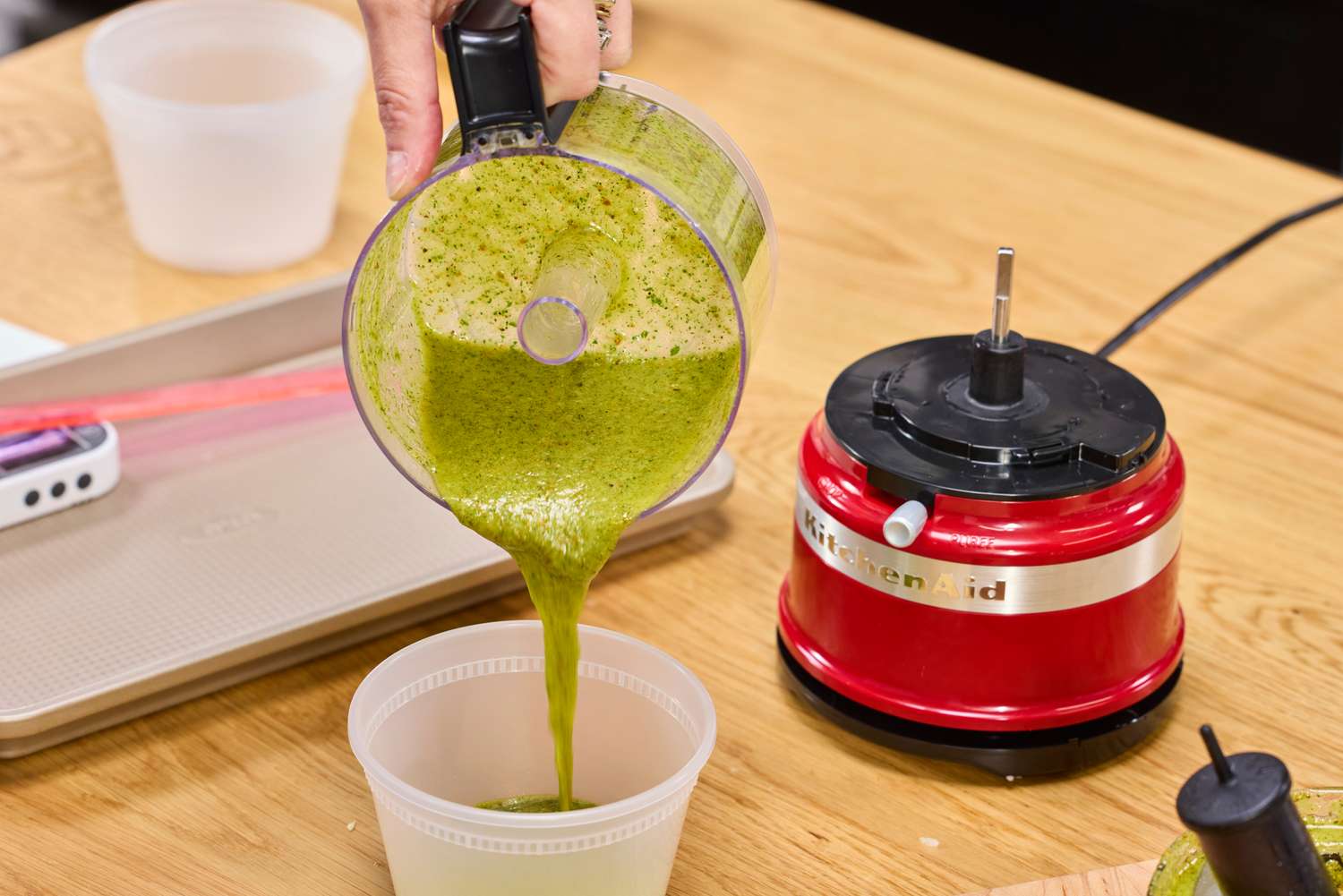 a person pours pesto from a food processor