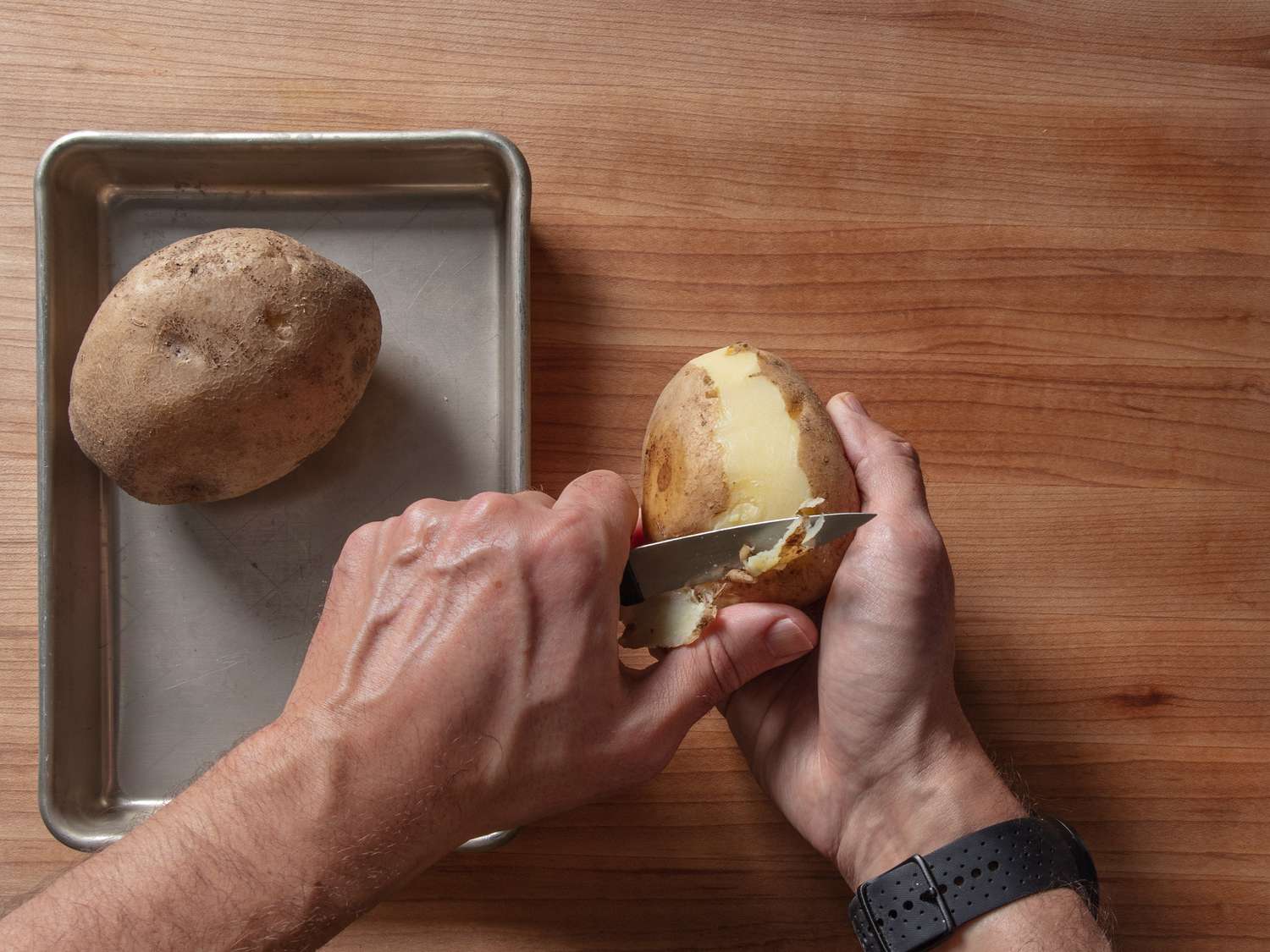 Peeling cooked and chilled Yukon Gold potatoes with a paring knife.