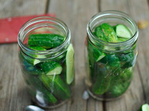 Two glass canning jars holding cut up cucumbers destined to become pickles.