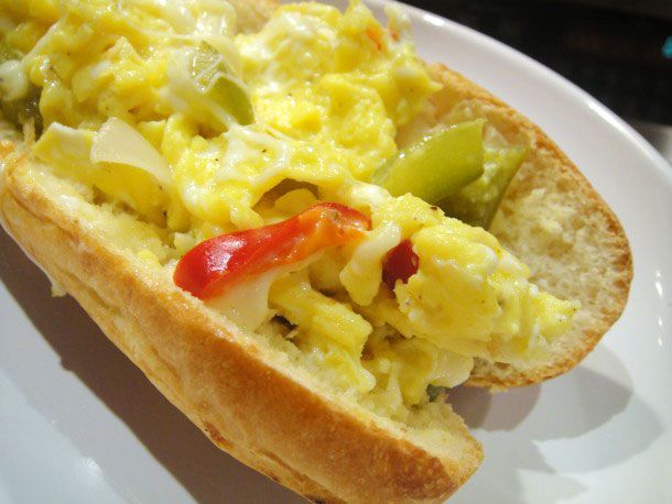 A Peppers and Eggs Sandwich on a white plate. 