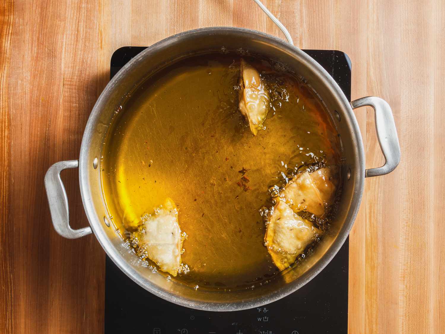 Kheema samosas viewed from overhead, frying in a pot of oil.