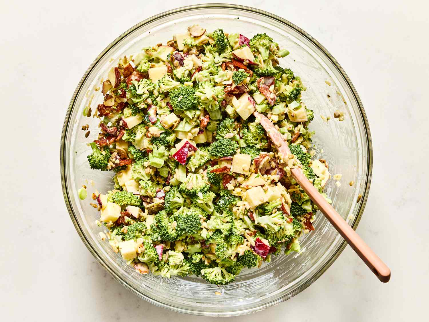 A bowl of broccoli salad with a wooden spoon