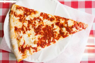 A slice of New York pizza (from Sac's Place) on a paper plate. 