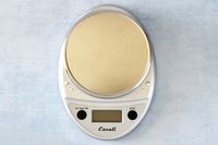 A silver Escali kitchen scale on a kitchen countertop.