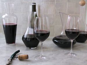 A collection of wine decanters filled with red wine on a marble counter