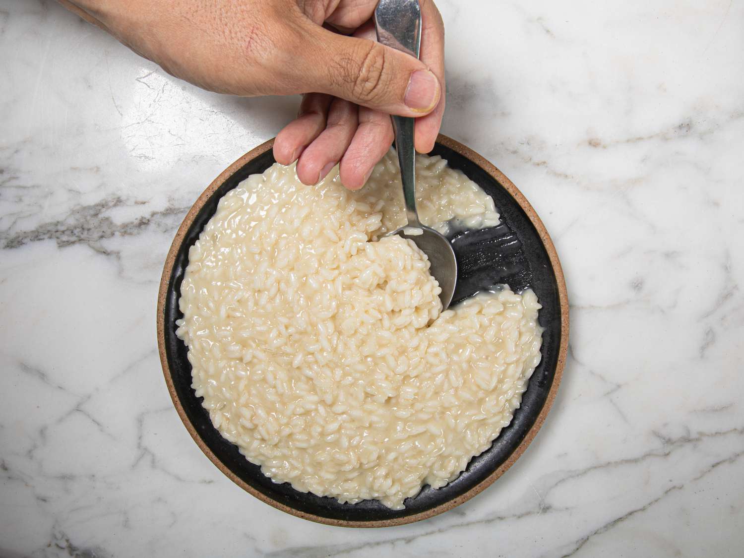 Overhead view of someone taking a spoon of risotto 