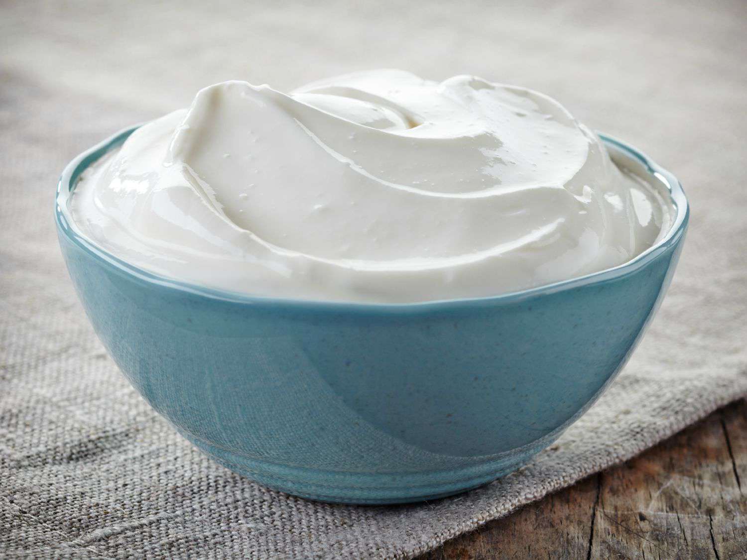 A small blue bowl full of sour cream. 