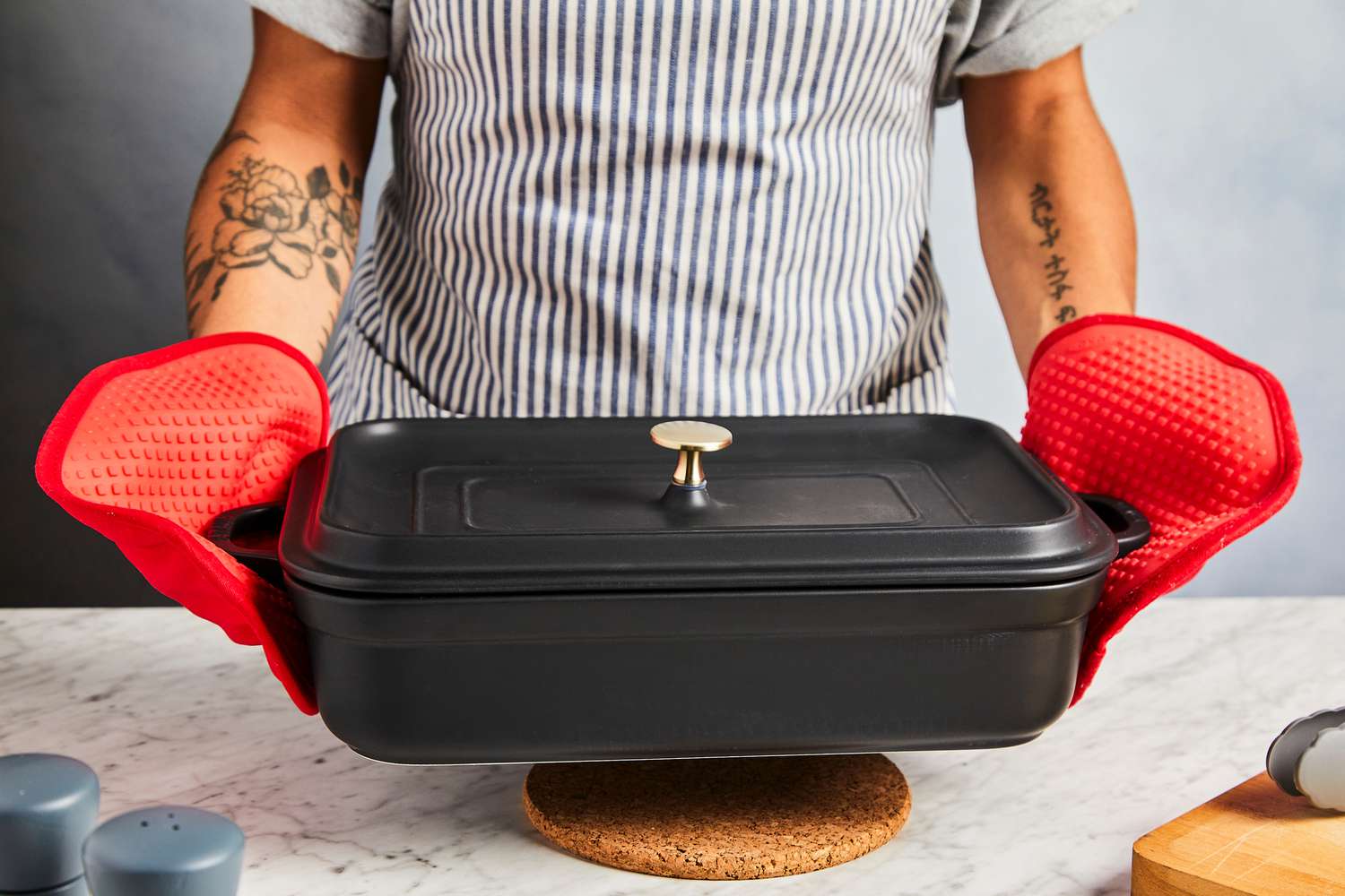 someone using oxo oven mitts to hold a casserole dish