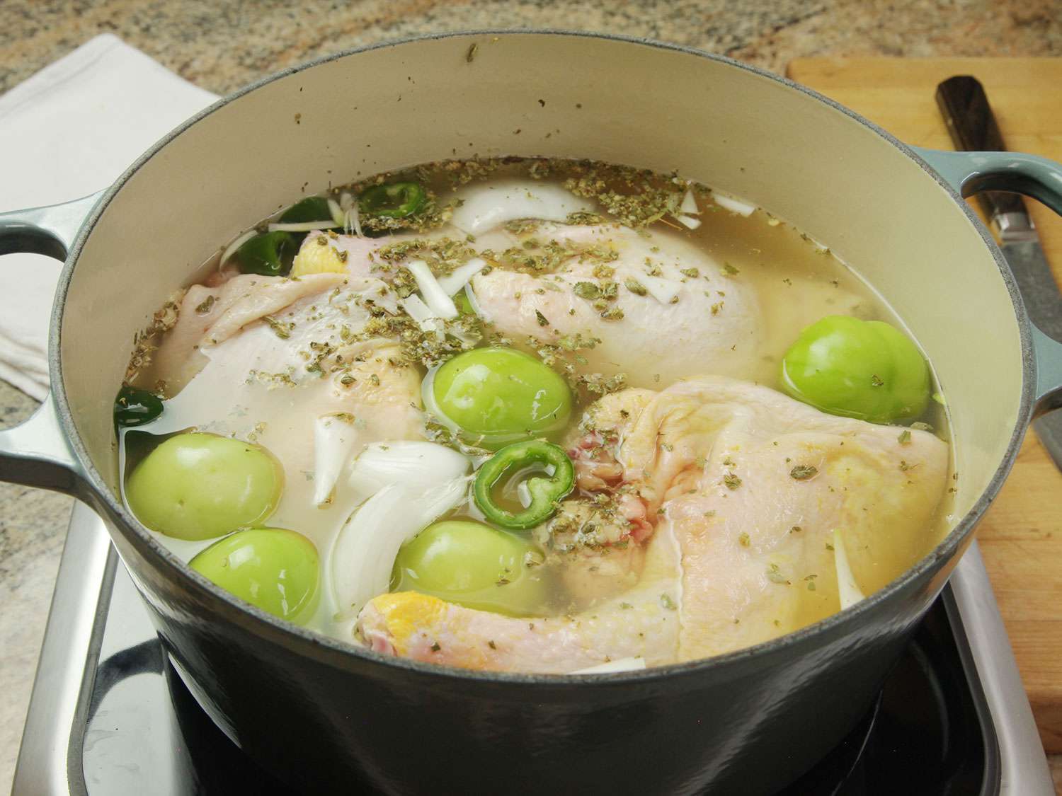 Chicken, tomatillos, and aromatics are brought to a simmer for pozole verde.