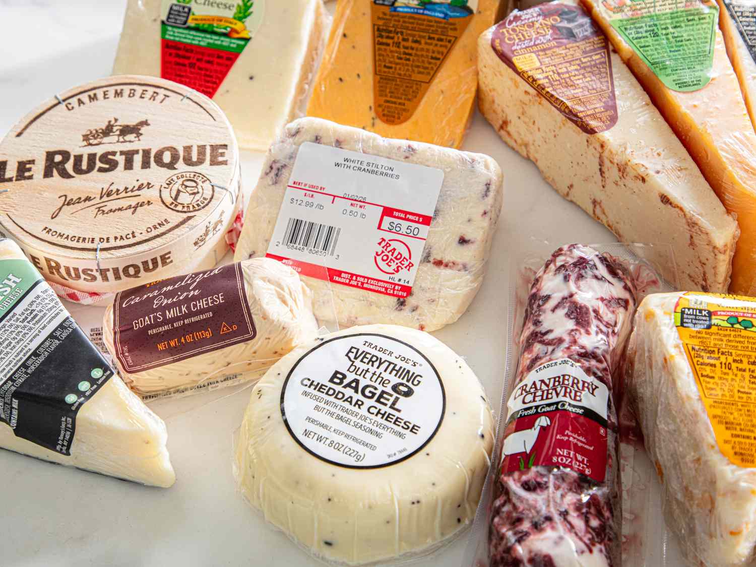 Assorted cheeses including Le Rustique Camembert and a selection of Trader Joes varieties arranged on a flat surface