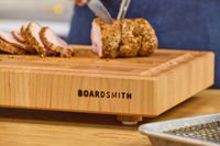 The Boardsmith Maple End-Grain Cutting Board holding a sliced roast being carved by someone