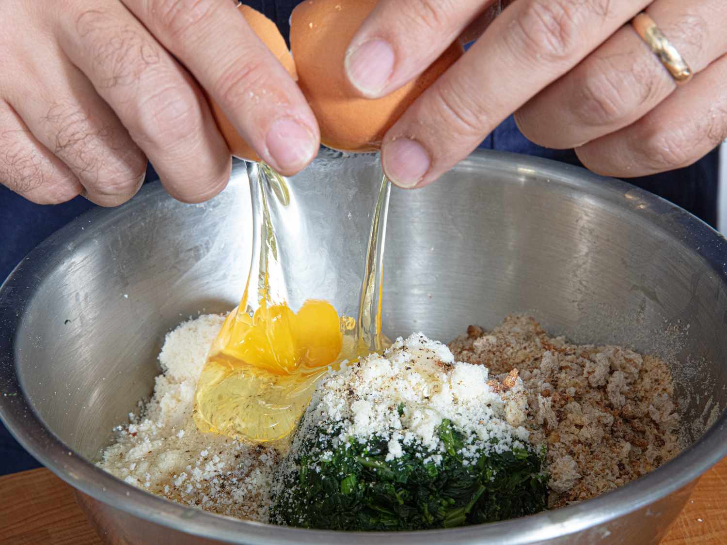 Ingredients in a bowl being mixed including eggs and spinach