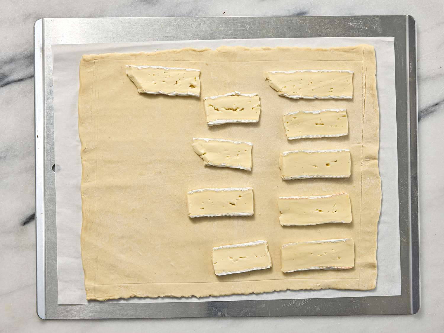 slices of brie on a tart on a sheetpan on a white marble surface 