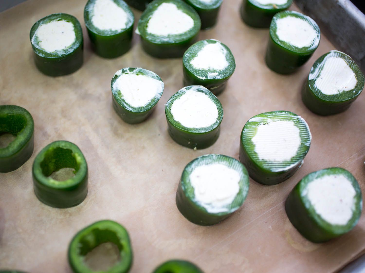 Filled jalapeño rings are transferred to parchment-lined baking sheet.