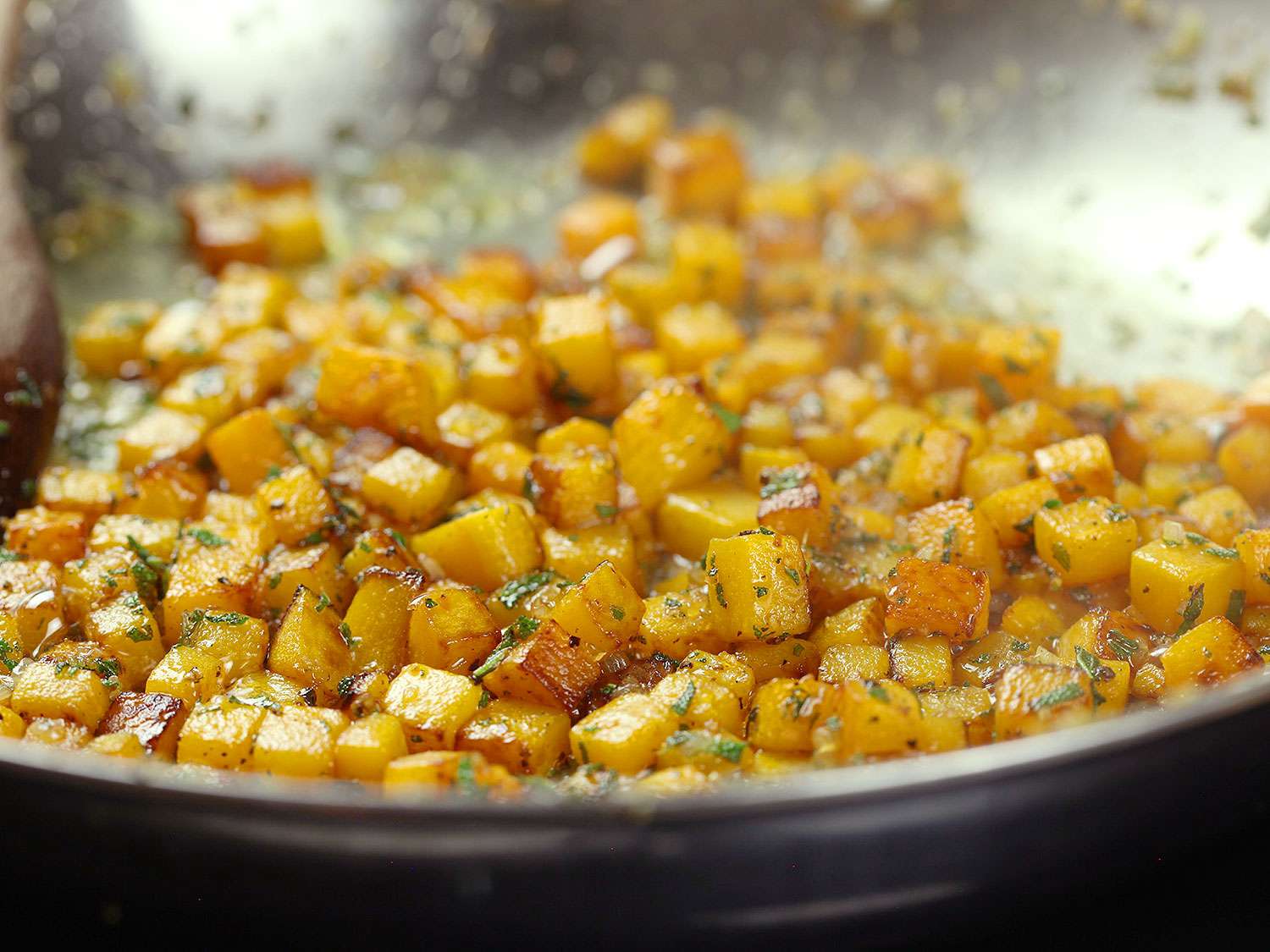 Butternut squash sautéing in a skillet.