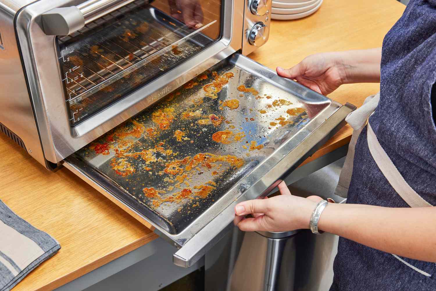 Two hands holding a dirty tray from the Breville the Smart Oven Air Fryer