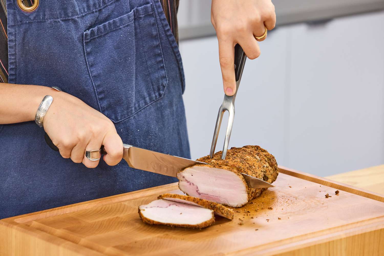 A person slices meat with the Wüsthof Classic Carving Set