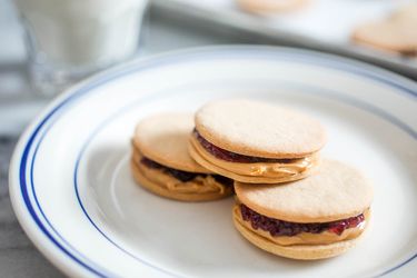 Closeup of PB&J sandwich cookies, stacked on a plate.