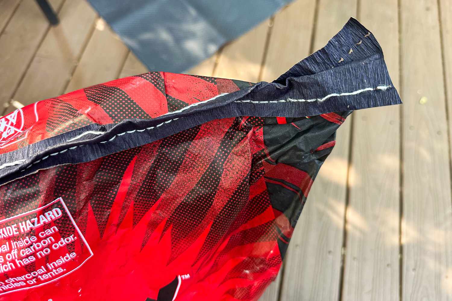 An opened bag of Jealous Devil Chunx Lump Charcoal with text warnings resting on a wooden surface