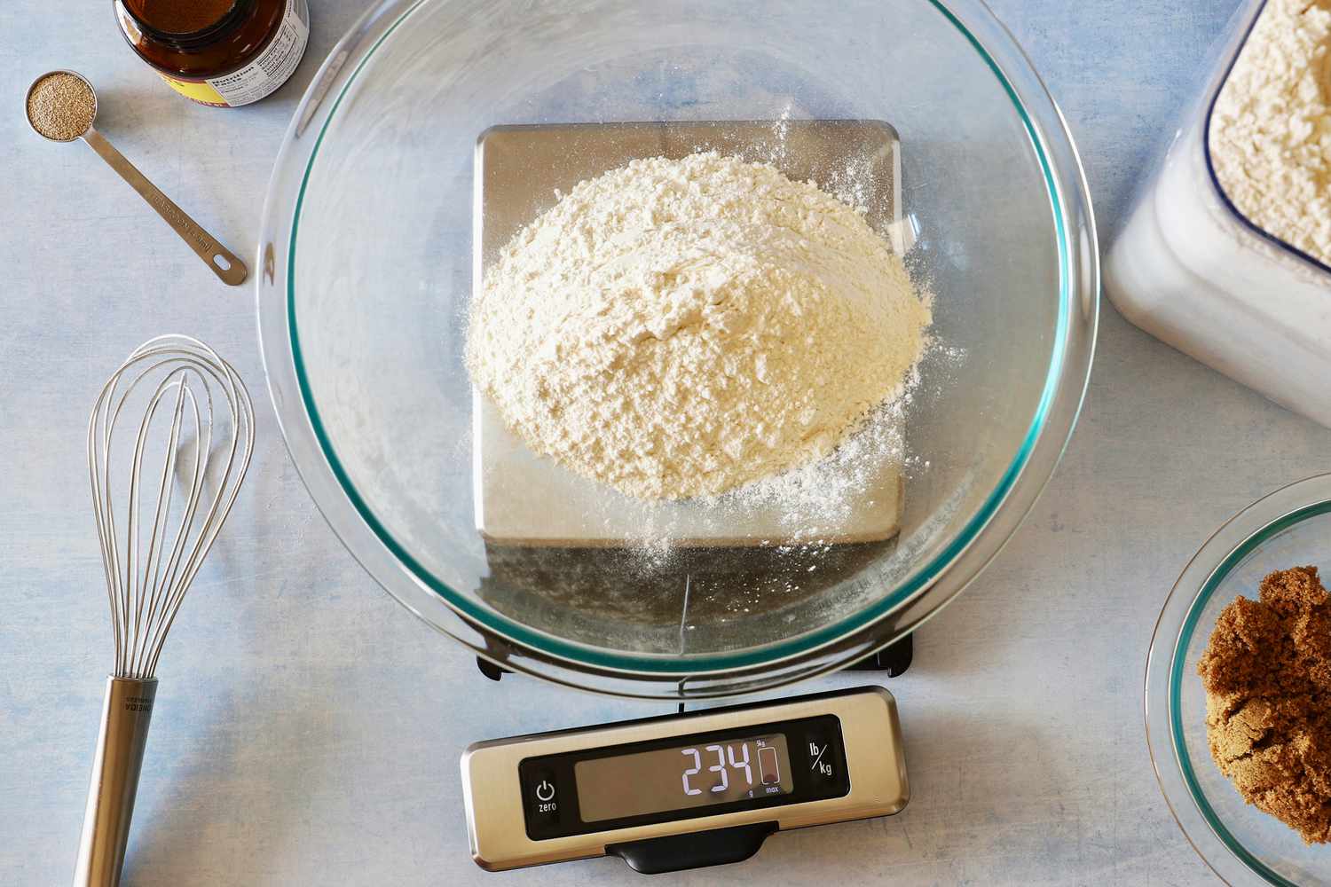 A glass bowl with flour on it set on a kitchen scale that has a pull-out screen.