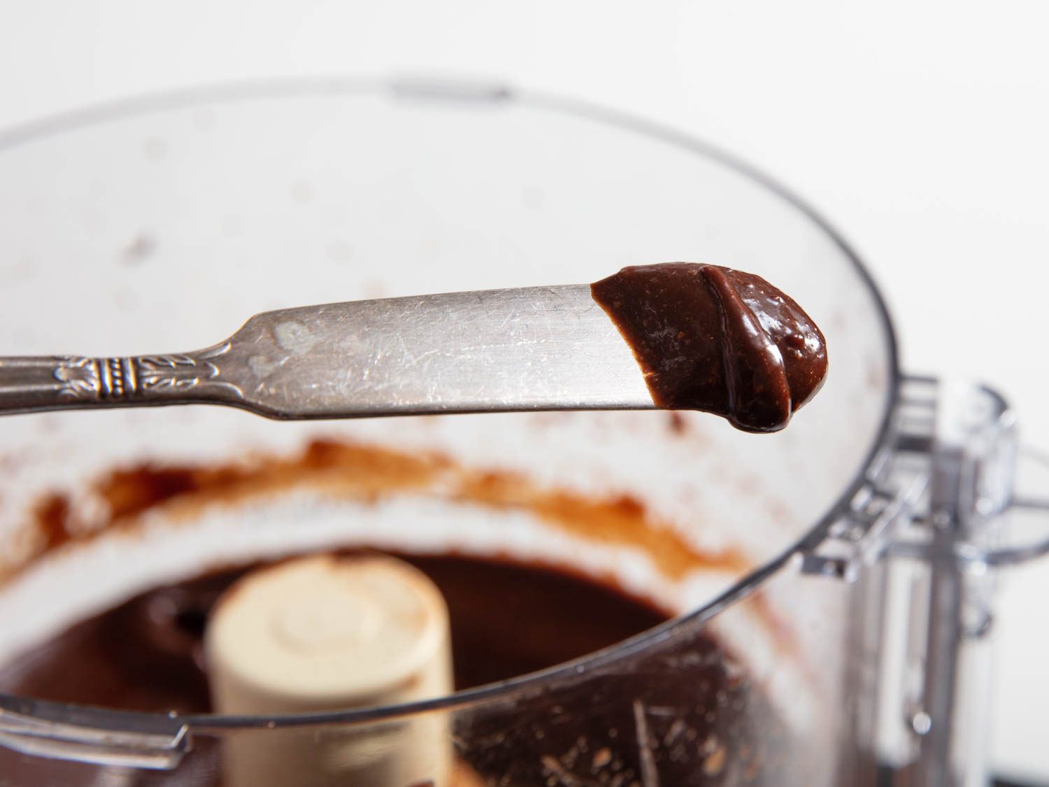 Closeup of a butter knife holding a dollop of creamy chocolate hazelnut spread up for the camera.