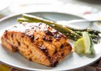 Broiled salmon with chile-lime mayonnaise, presented on a plate with lime wedges and asparagus.