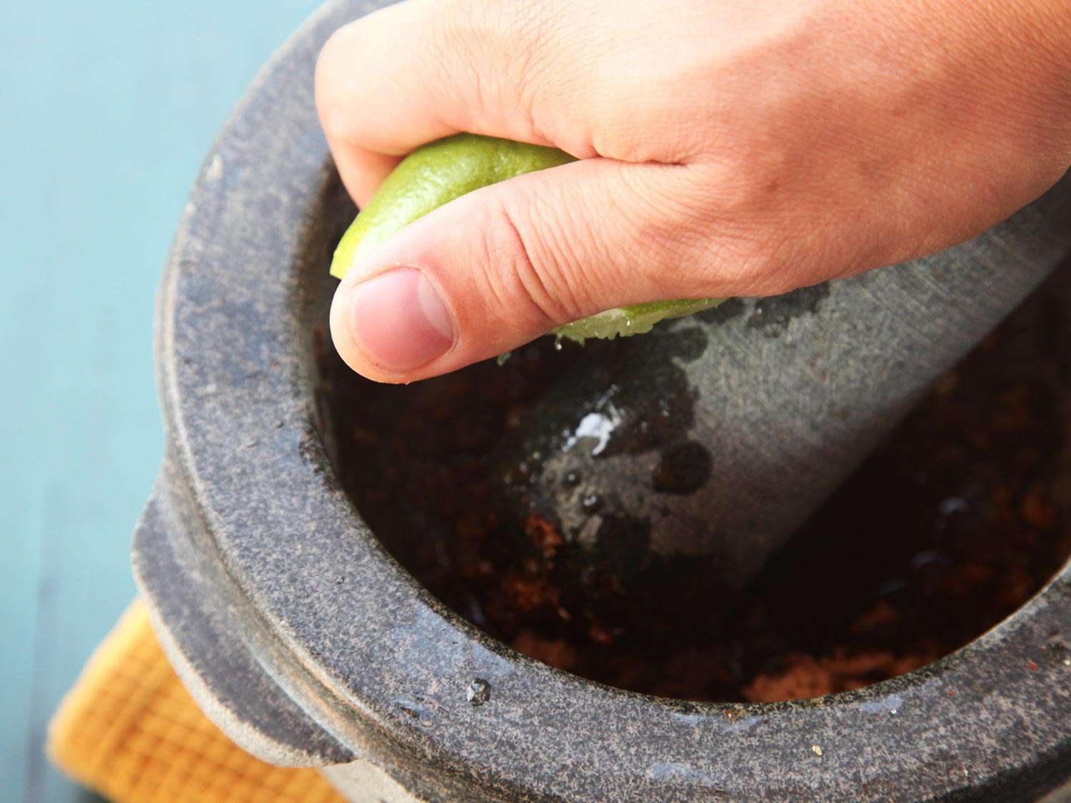 Squeezing lime into the dressing in a mortar for sliced-steak salad. 