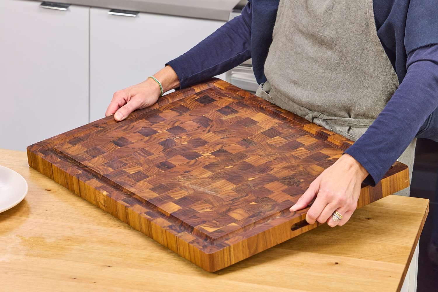 Person placing a Yes4All Teak Cutting Board on a kitchen counter