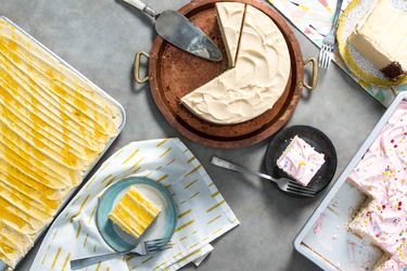 Overhead shot of a round layer cake, sheet cake, and rectangular cake with portions cut out and plated.