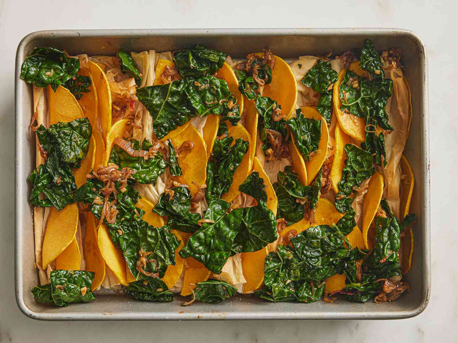 Kale and vegetables into layers on sheet pan 