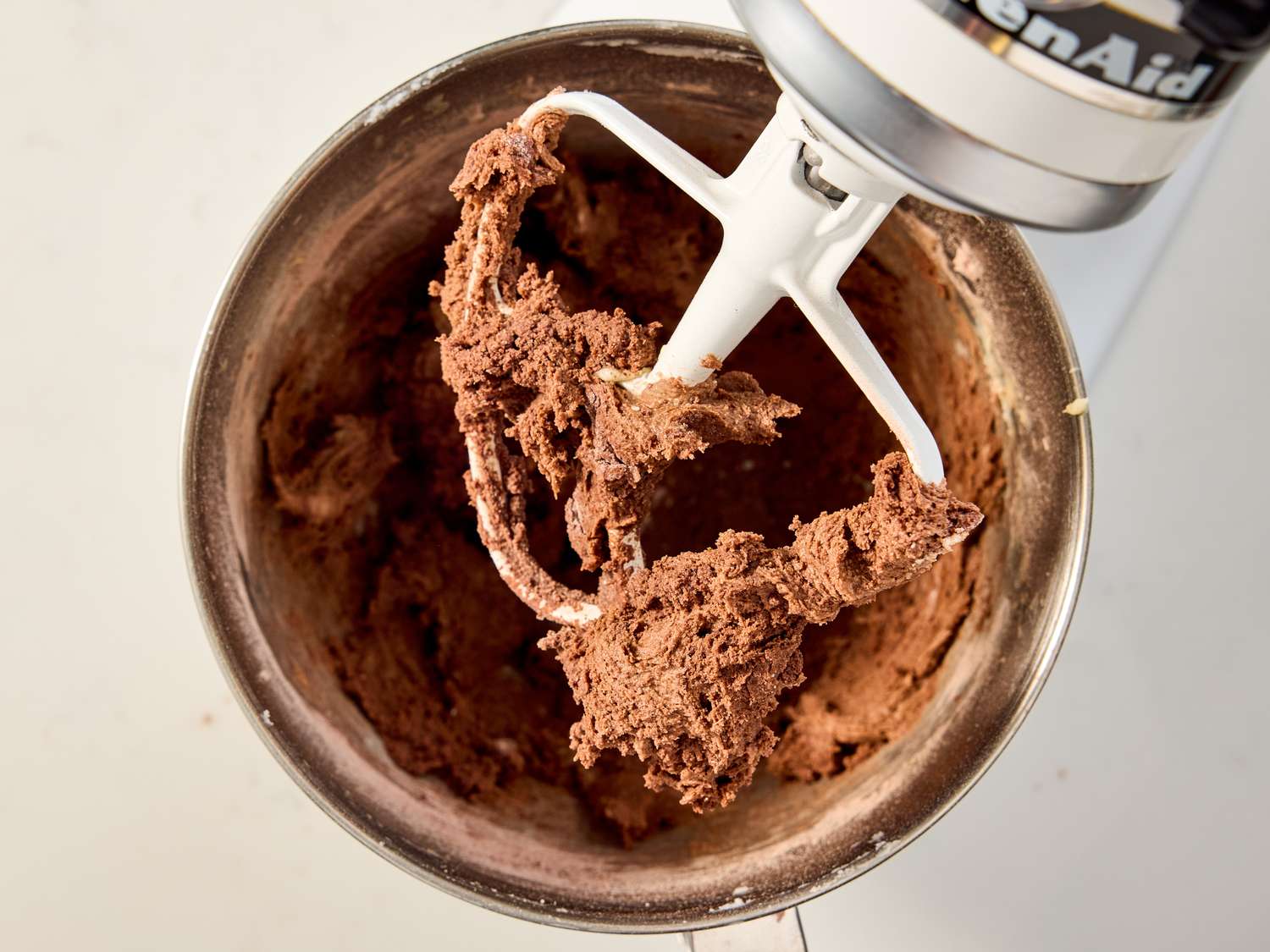 Chocolate cookie dough being mixed with a stand mixer paddle attachment