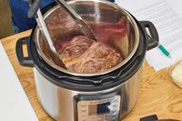 A piece of meat is placed in the Instant Pot Duo Plus 6-Quart 9-in-1 Pressure Cooker