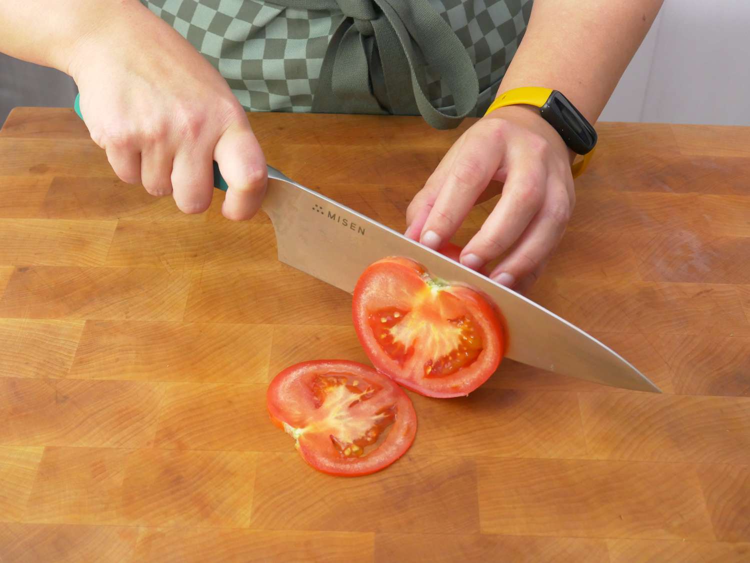 a person using the misen knife to slice a tomato