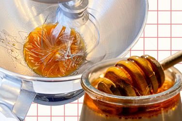 A stand mixer whipping honey next to a jar of honey. 