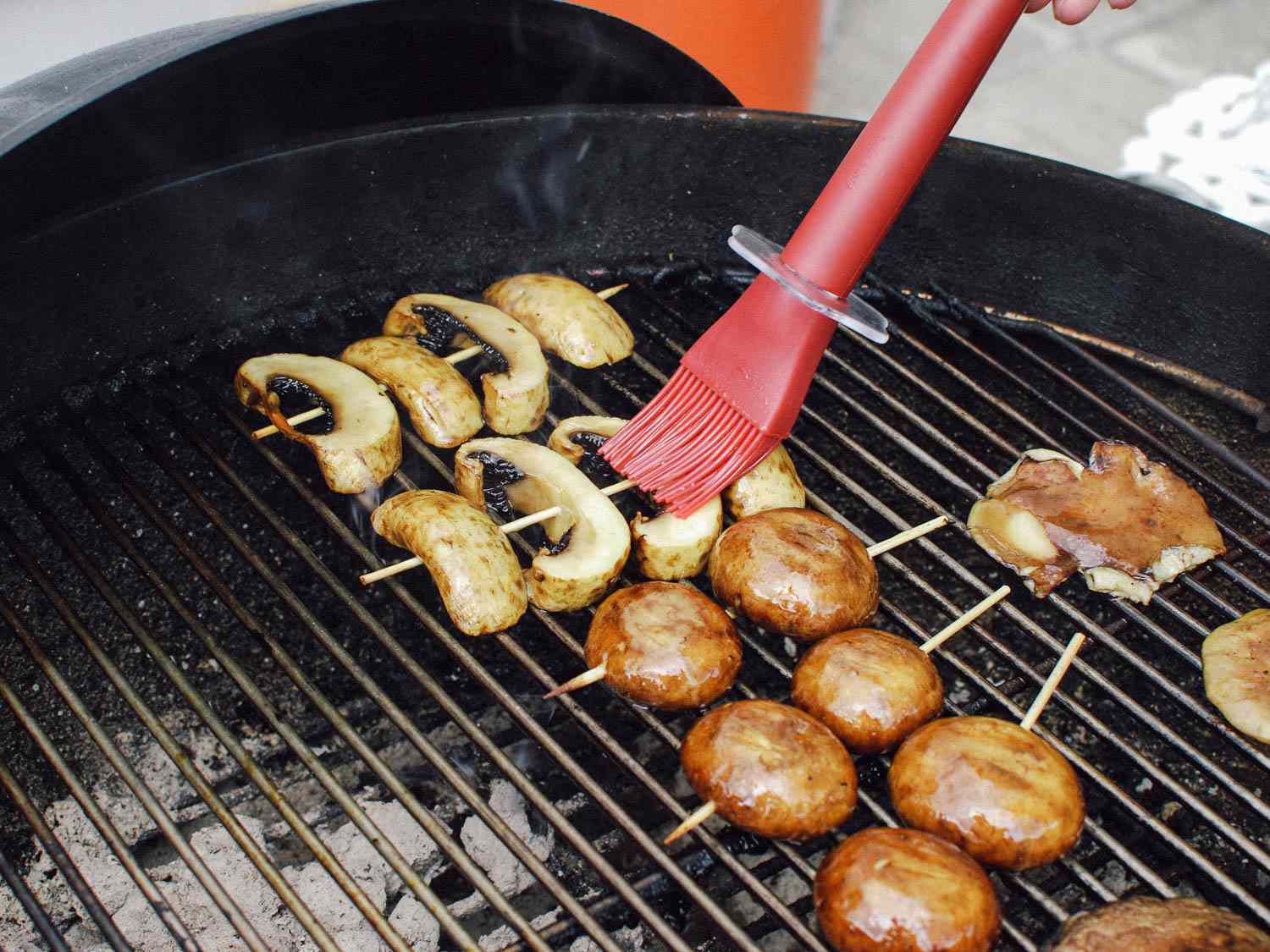 Brushing grilling mushrooms with butter and soy sauce to keep them moist.
